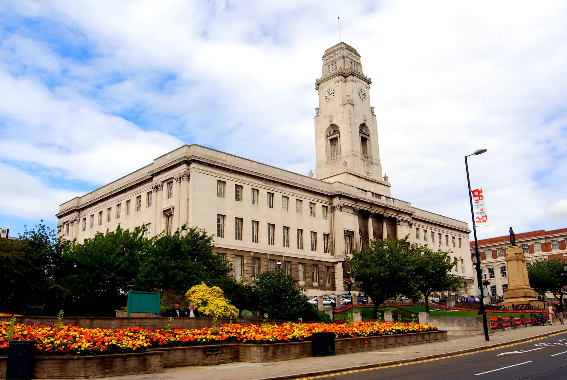 Barnsley Town Hall's white stone clock tower above flower beds in full bloom