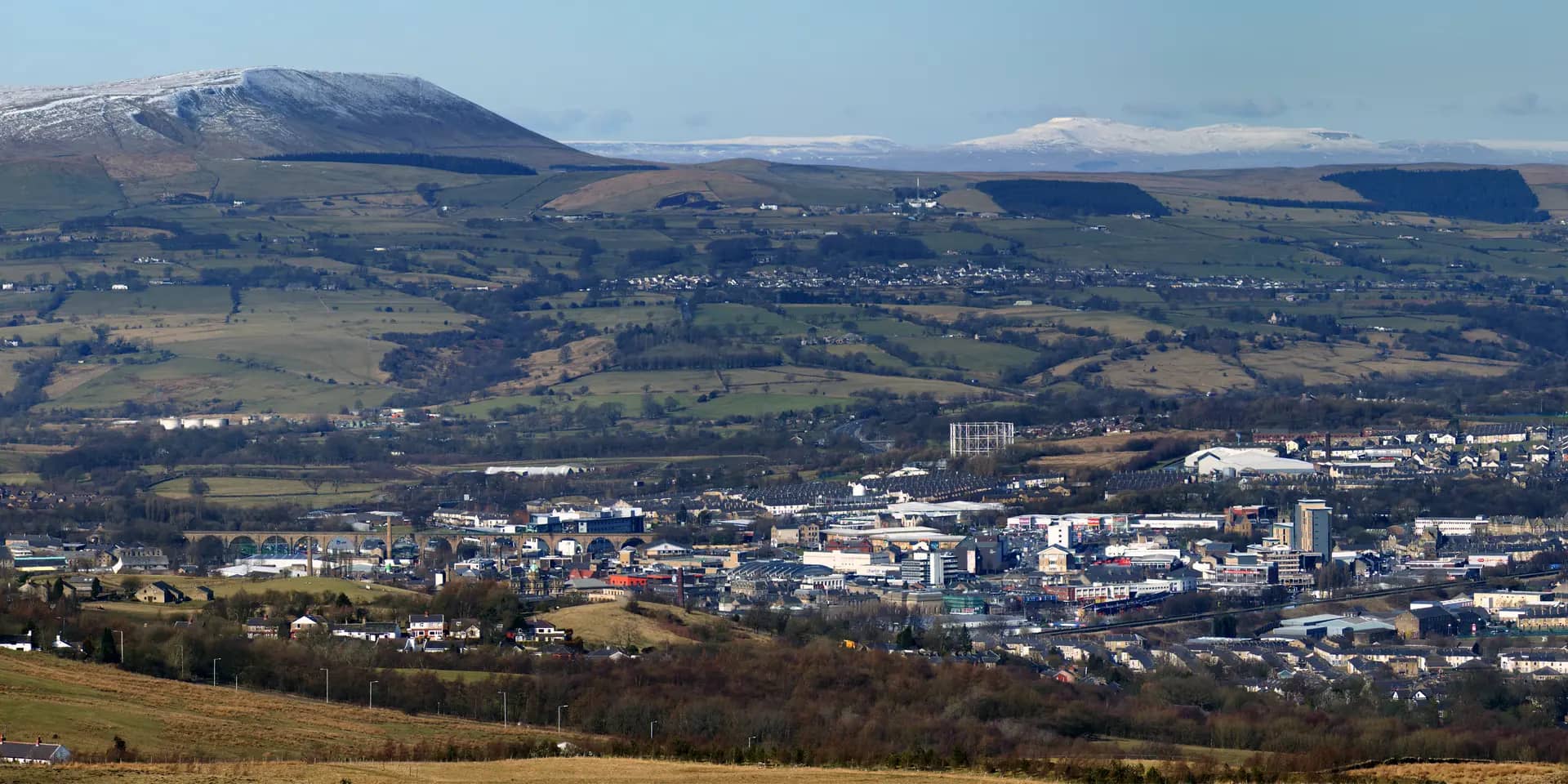 Burnley town centre and its surrounding streets seen from Crown Point, with snow-capped Pendle Hill beyond