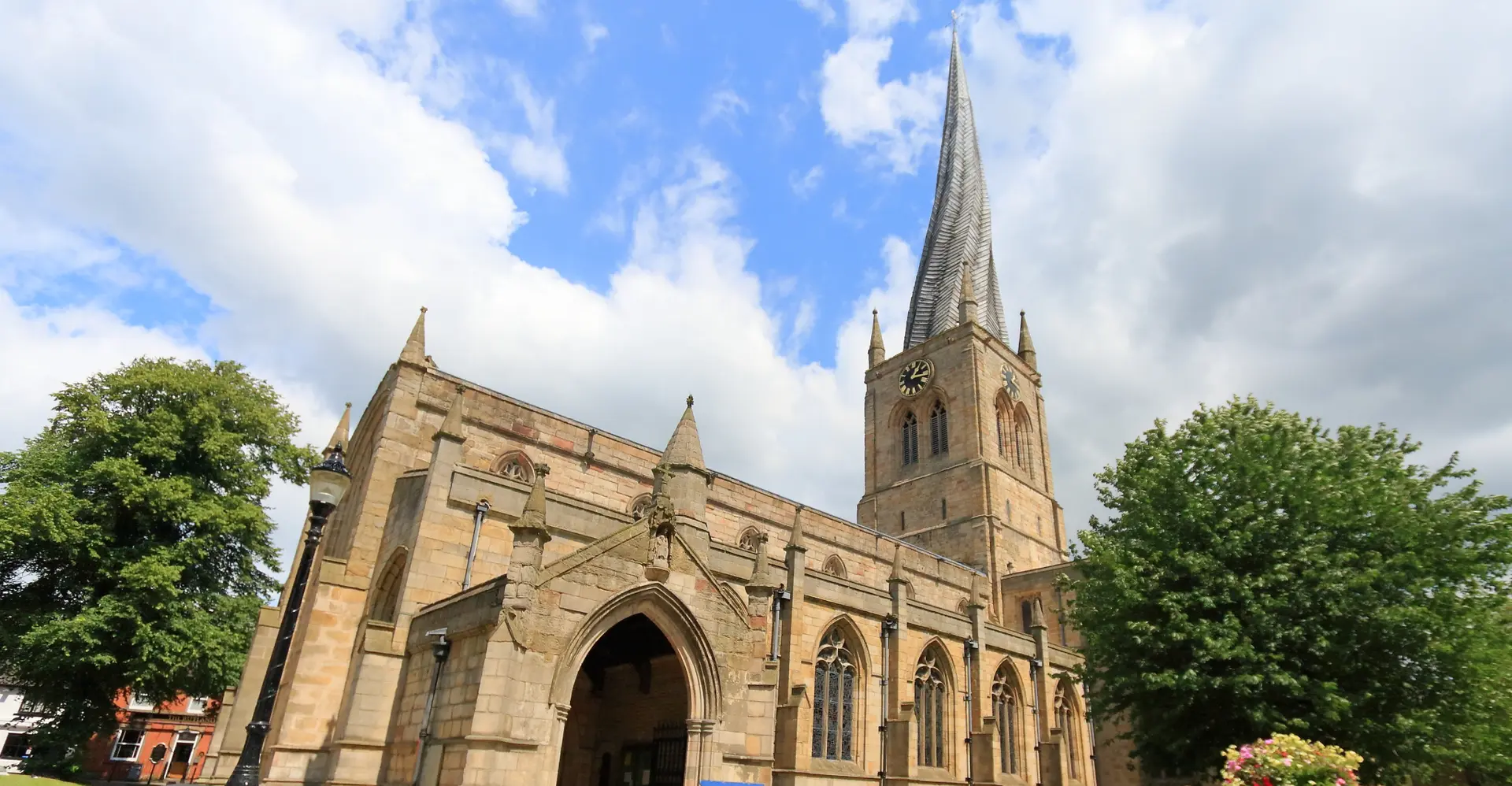 The twisted, leaning crooked spire of Chesterfield's Church of St Mary and All Saints against a blue, cloudy sky