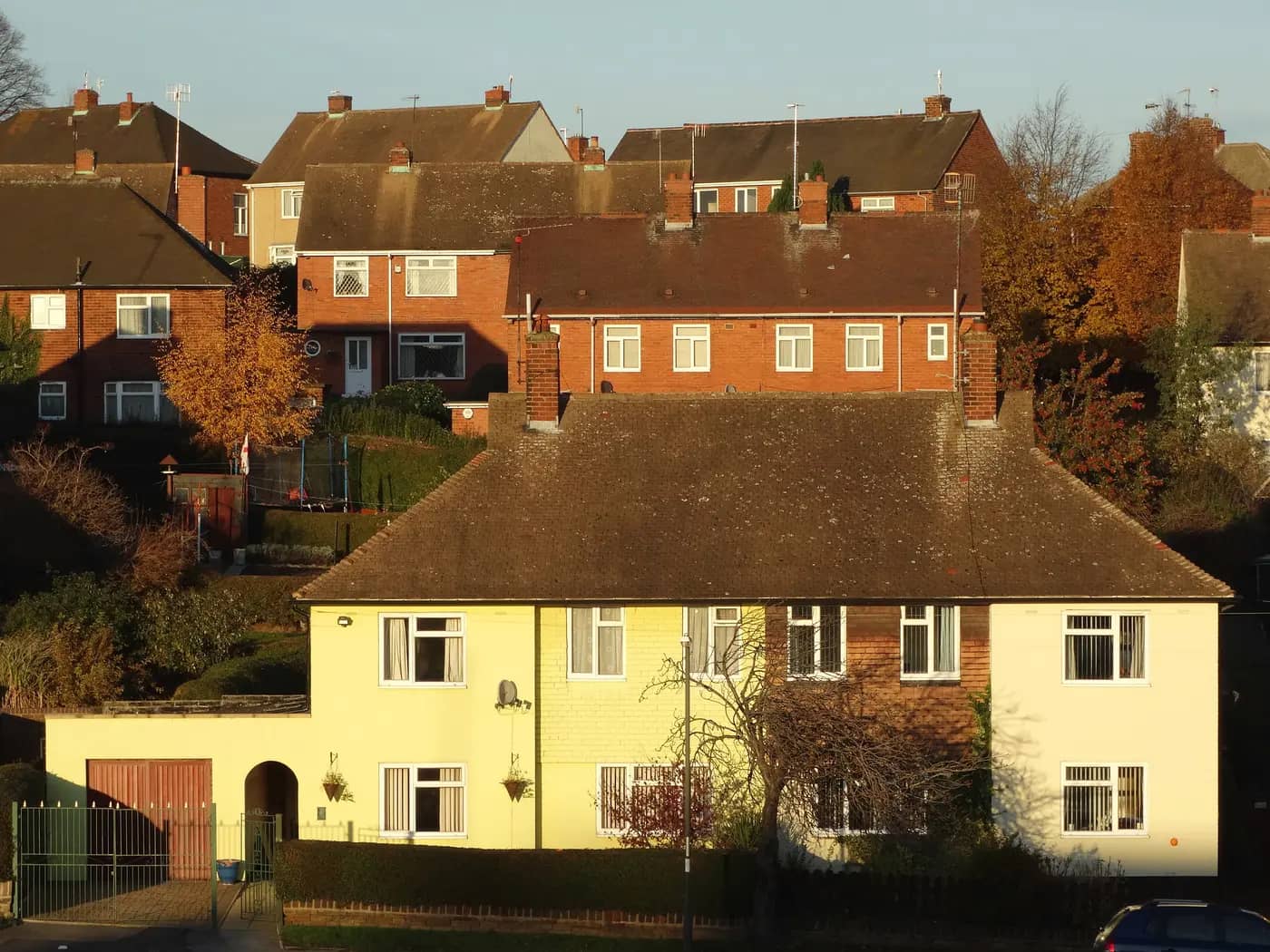 Red-brick semi-detached houses climbing the hillside in Stonegravels, Chesterfield, lit by low autumn sun
