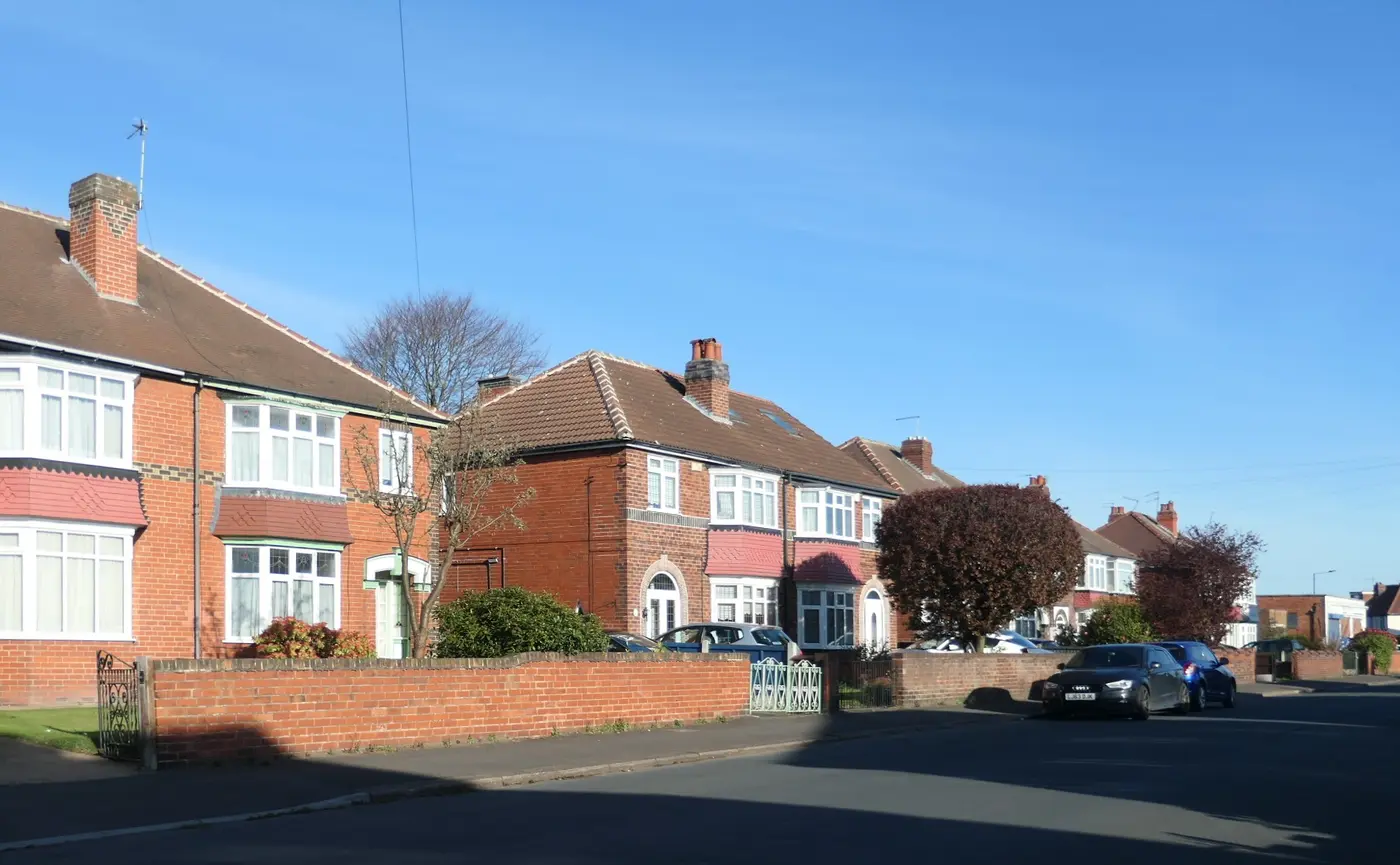 Red-brick 1930s semi-detached houses with bay windows on Sandall Rise, Doncaster, under a blue sky