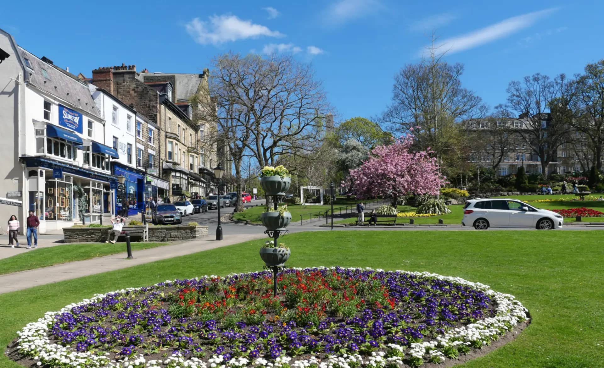 Montpellier Gardens in Harrogate in spring, with flower beds, blossom trees and the stone buildings of Montpellier Parade