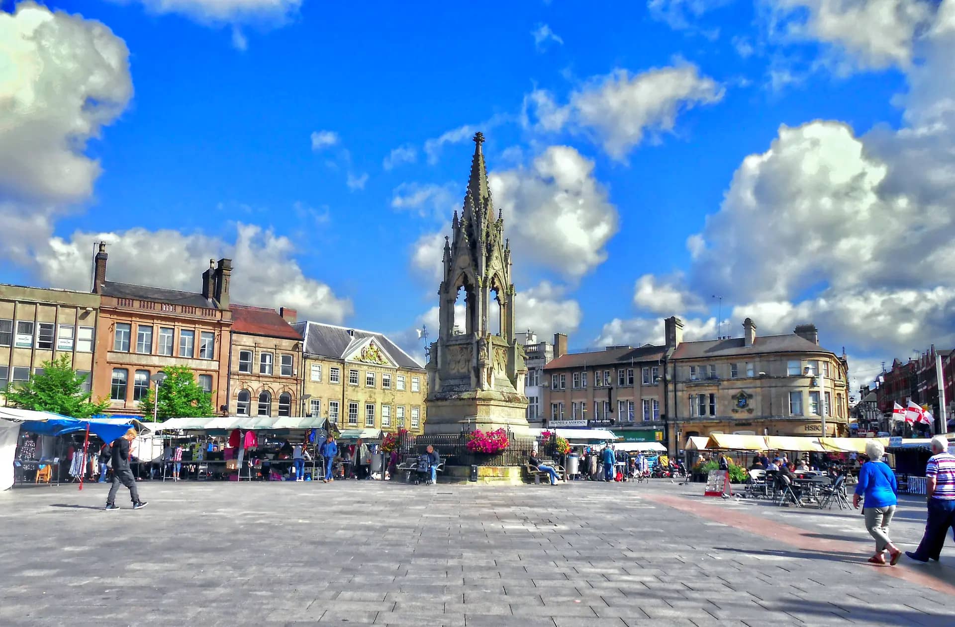 Mansfield Market Place on market day, with the Gothic Bentinck Memorial and surrounding buildings under a blue sky