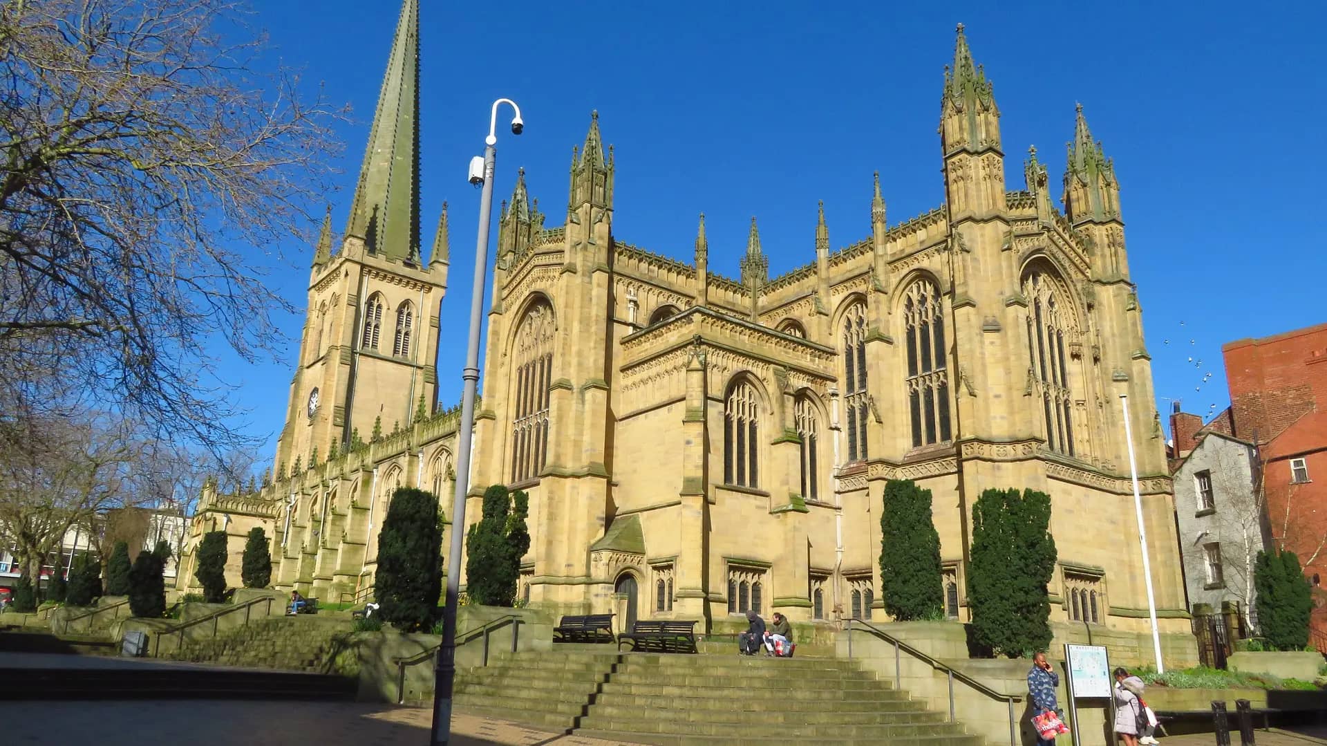 The spire and golden sandstone walls of Wakefield Cathedral under a deep blue sky