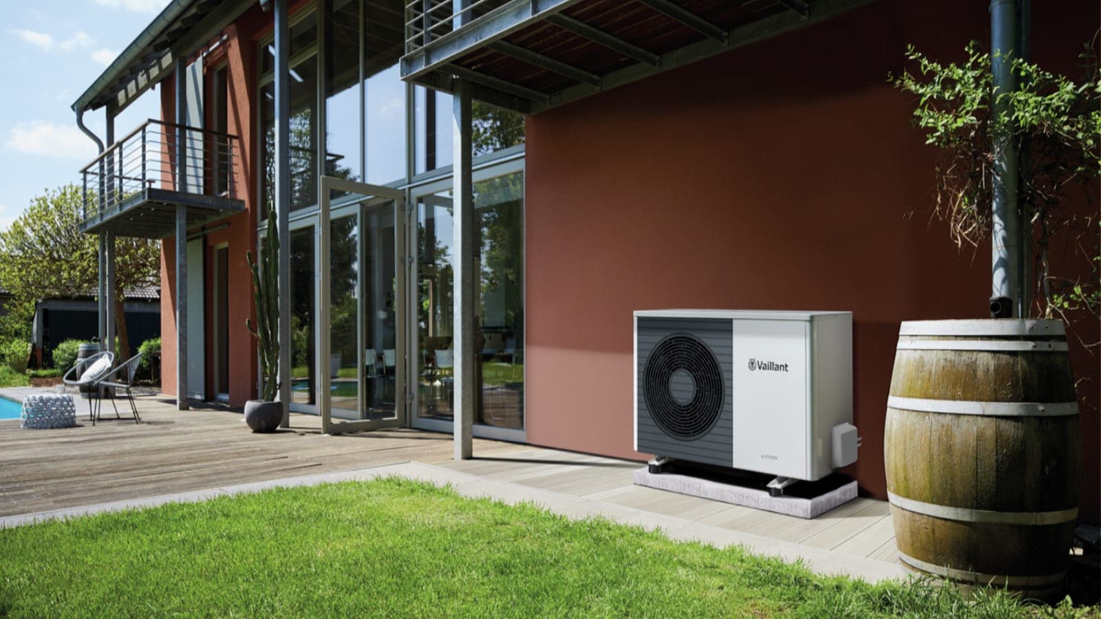 An air source heat pump standing on a patio beside a timber-clad house