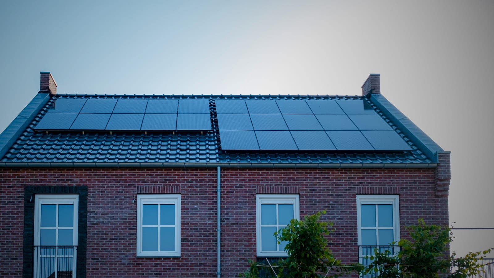 A brick house with a full array of all-black solar panels across the main roof
