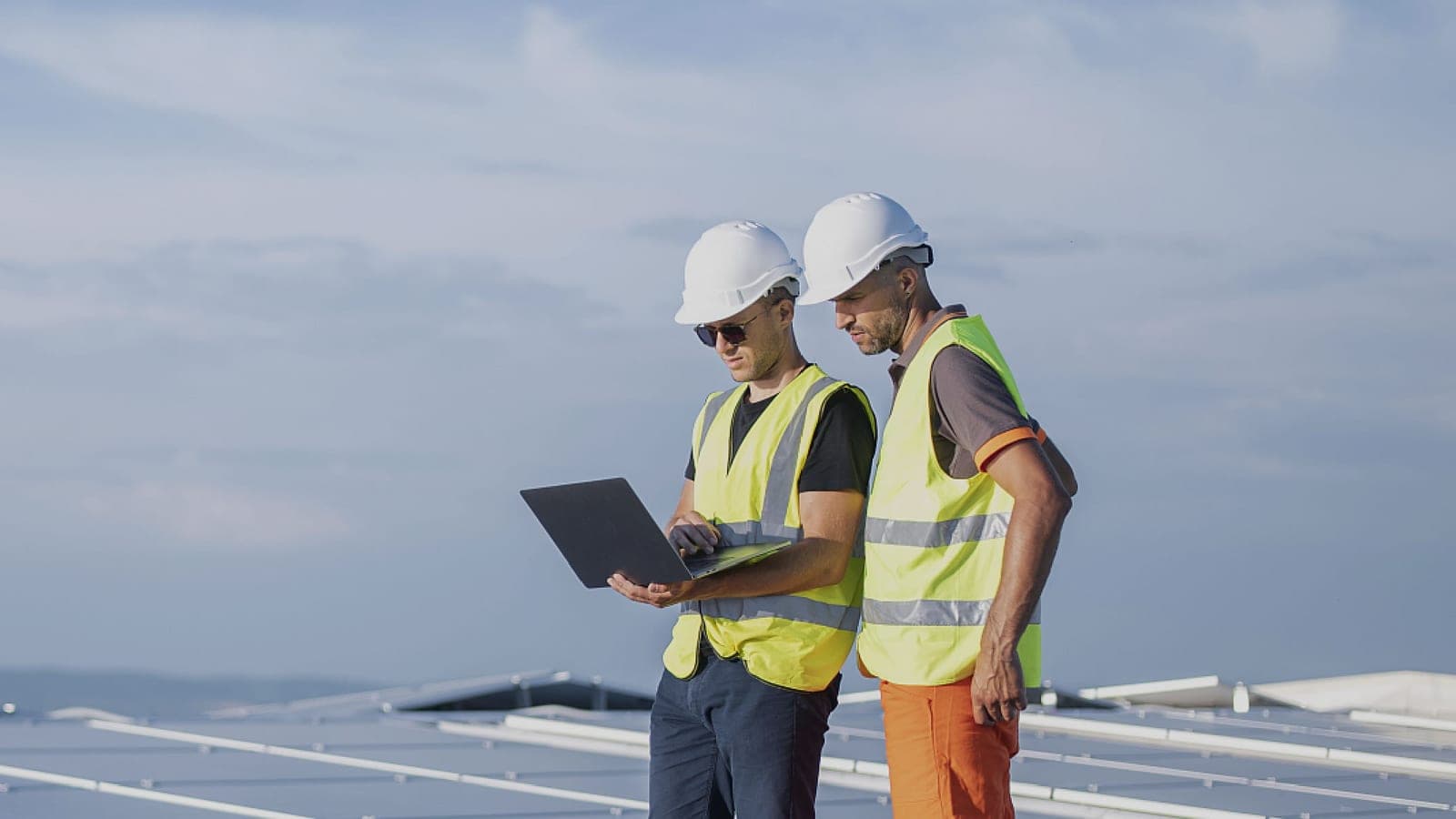 An engineer with a laptop on a commercial roof covered in all-black solar panels