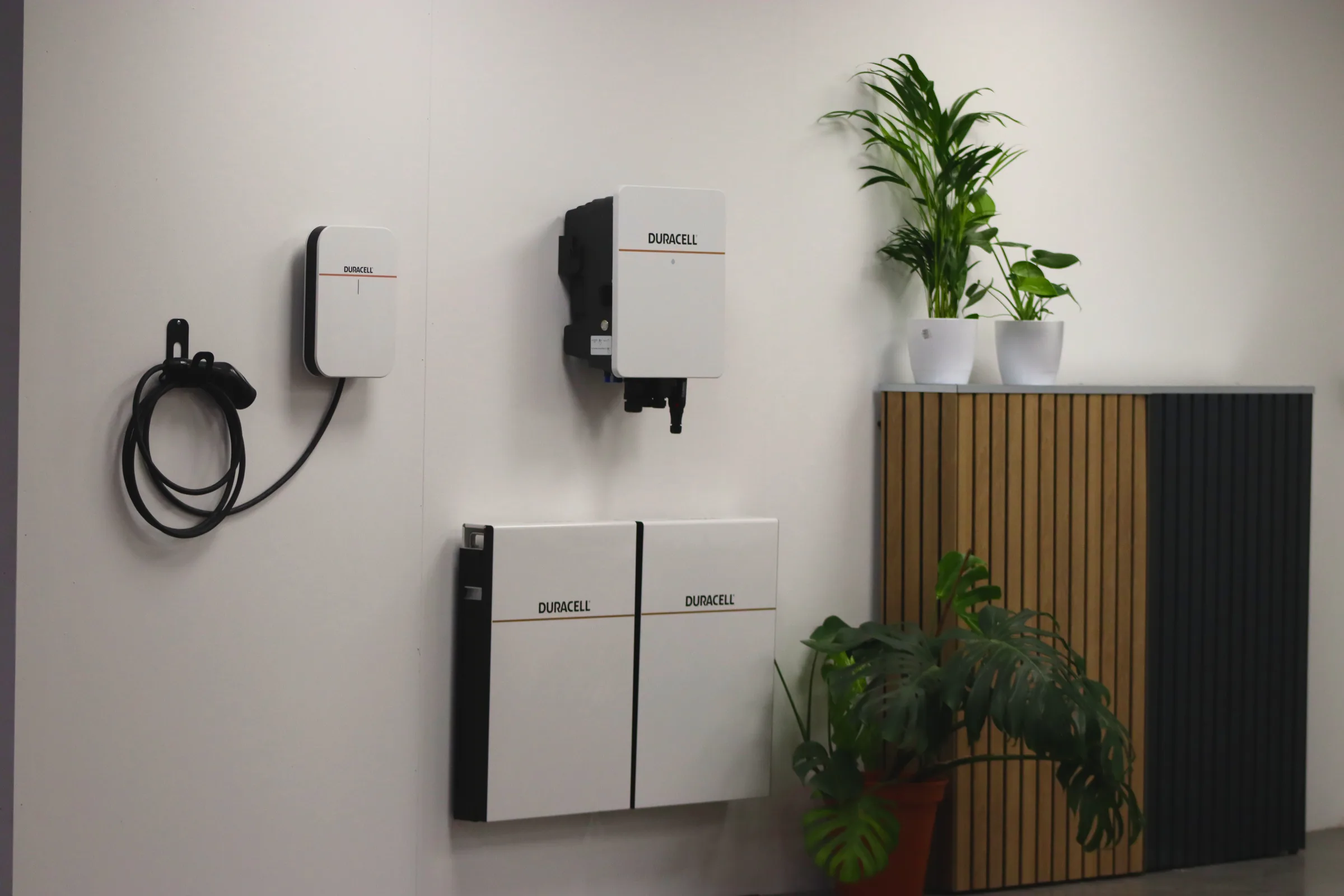 A charger, an inverter and two battery modules fitted together on a plastered wall