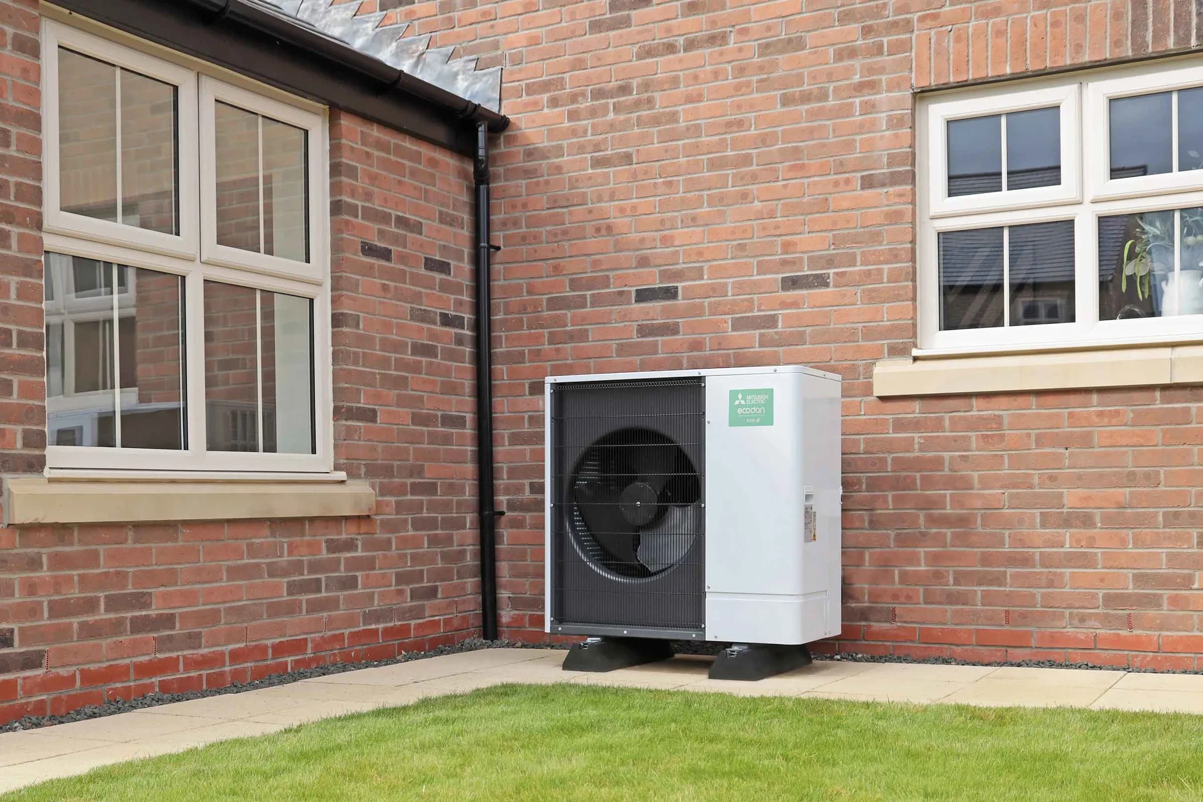 An Ecodan R290 heat pump on the gable wall of a red brick house