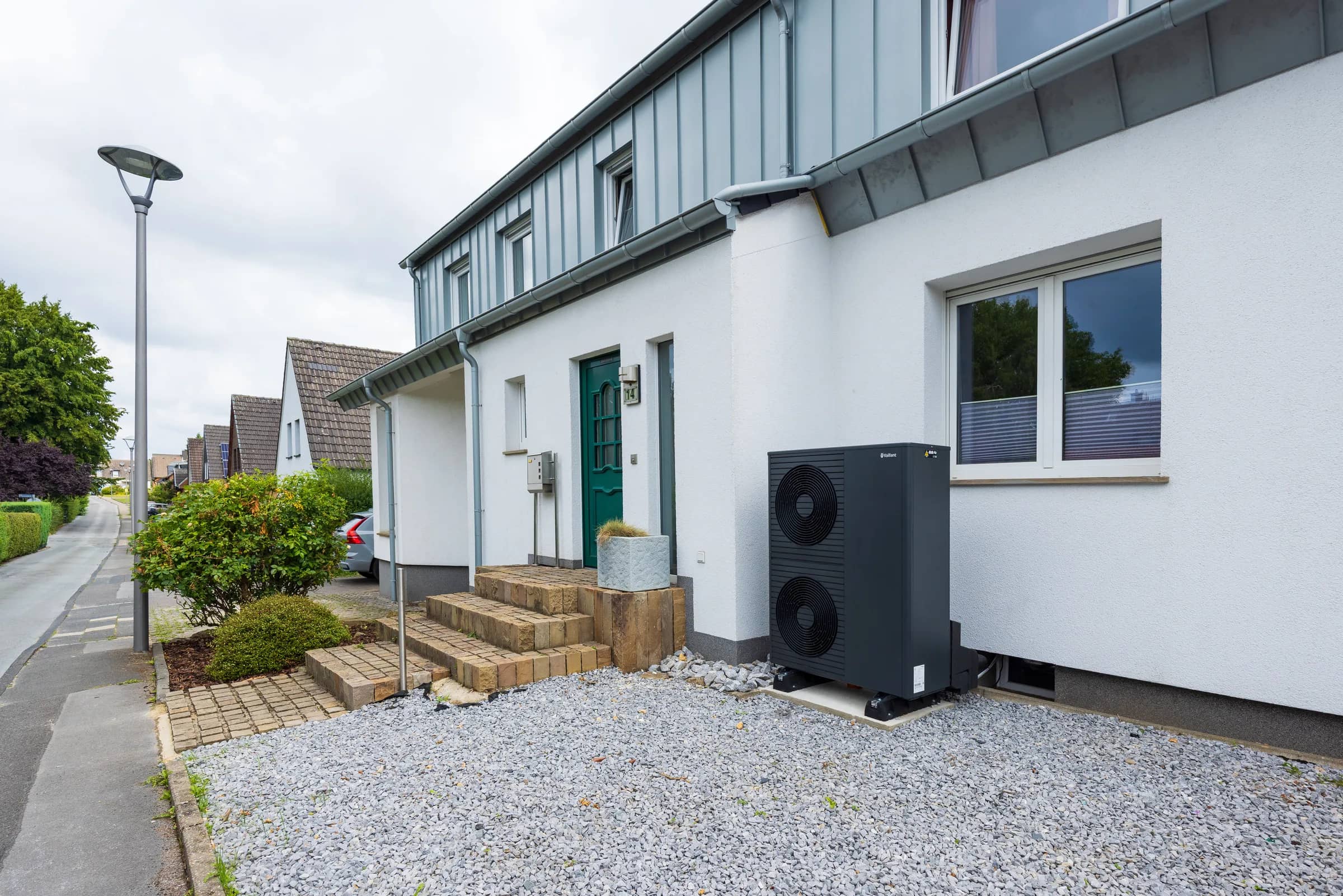 A Vaillant aroTHERM plus heat pump outside a white rendered house